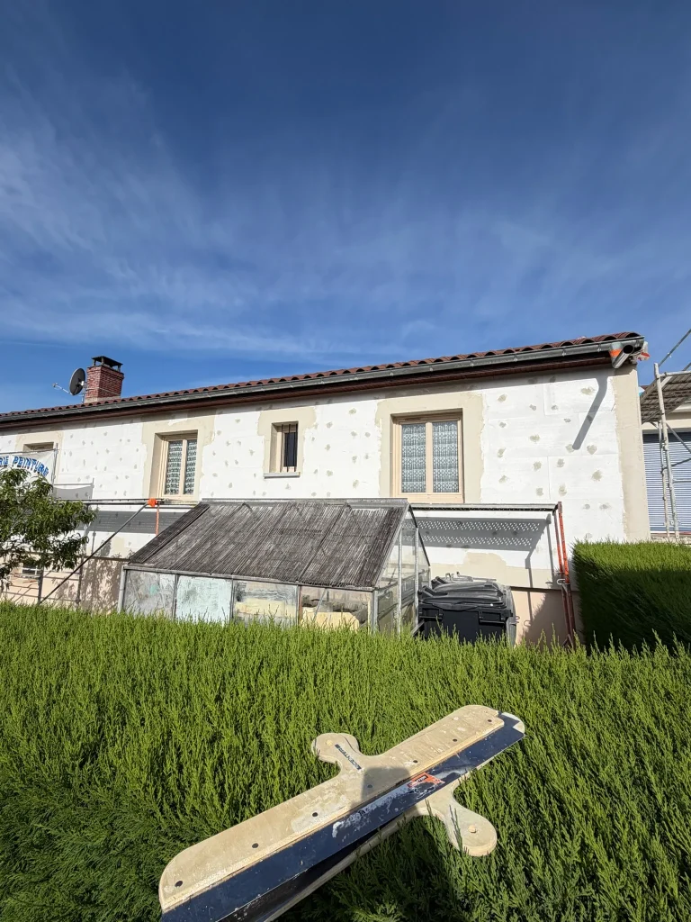 Façade claire d'un bâtiment avec échelle, échafaudage sur le côté et protections devant les fenêtres