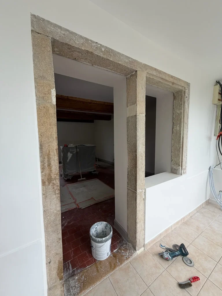 Murs blancs autour de deux ouvertures encadrées de pierre dans une pièce en rénovation