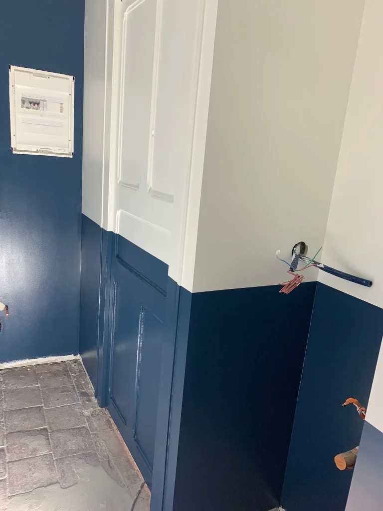Mur blanc à soubassement bleu, porte blanche et branchements en attente