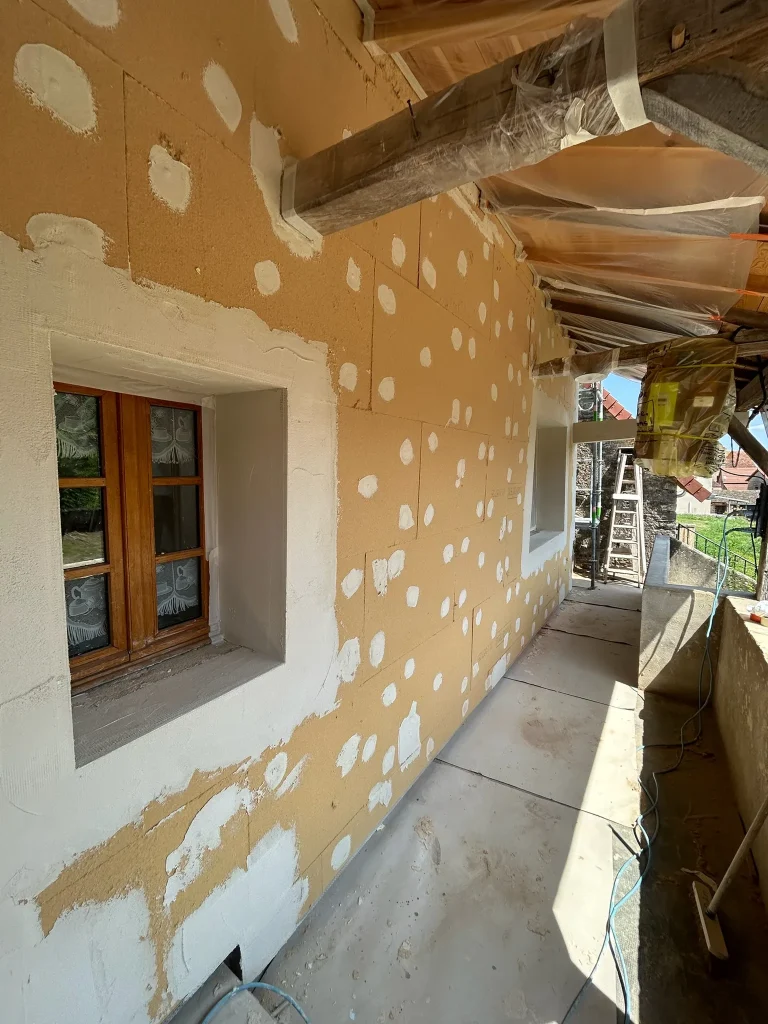 Panneaux d'isolant sur une façade sous auvent, fixations et enduit autour des fenêtres