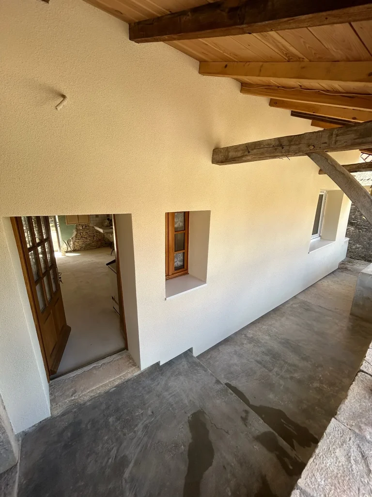 Façade claire sous auvent en bois avec portes et fenêtres et protections au sol