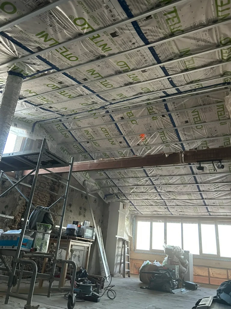 Combles en chantier avec membrane sous toiture, ossature et charpente apparente